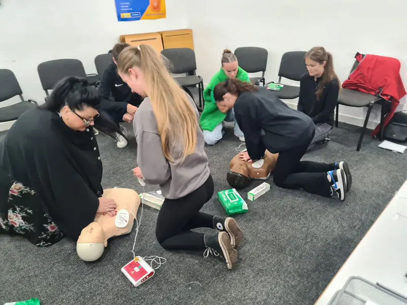 Learners practising CPR and using AED training equipment