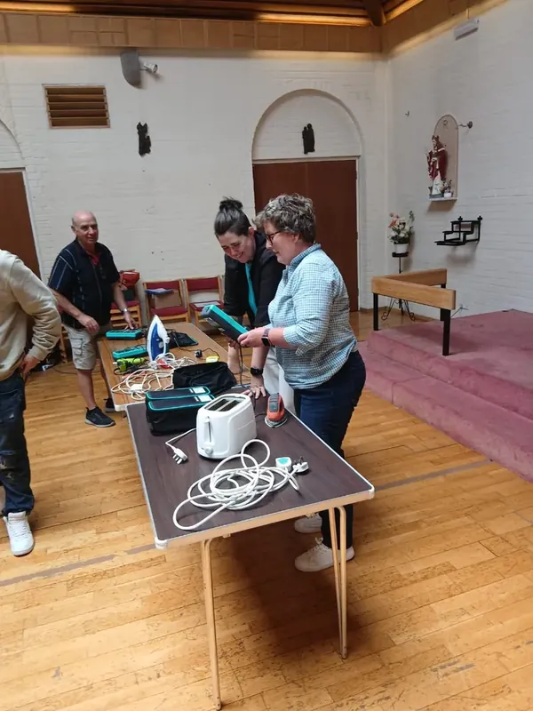 A group working with appliances and PAT testers during training